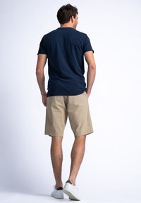 Navy short-sleeve shirt paired with beige shorts, both in solid colors. The shorts have a relaxed fit, reaching mid-thigh length, with a smooth texture.