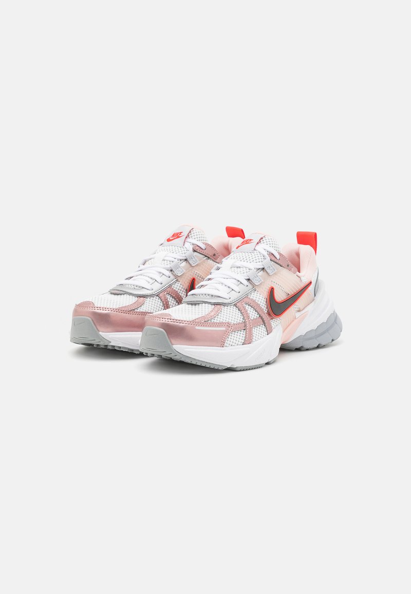 Scarpe Nike con tomaia in rete bianca e rosa chiaro, dettagli grigi e accenti rossi, caratterizzate da un design con suola chunky.