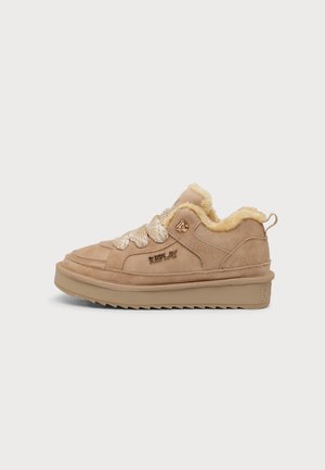 Zapatilla de ante beige con suela gruesa, cordones beige con patrón y forro de pelo suave visible alrededor del cuello del tobillo. Nombre de la marca "Replay" en el lateral.