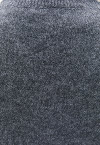 Texture de pull en tricot de couleur gris foncé avec une finition grossière. Présente un col côtelé et de fines fibres duveteuses sur l'ensemble du tissu.