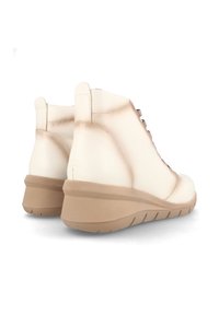 Botines beige con cuero suave, puntera redondeada, diseño de cordones y tacón en cuña acolchado con acentos texturizados.