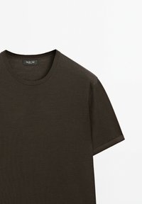 Tmavě hnědé bavlněné tričko s kulatým výstřihem a krátkými rukávy. Hladký materiál, jednoduchý design a nenápadná značka na límci.