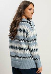 Maglione a maglia azzurro chiaro con un motivo geometrico in bianco e nero, con polsini e orlo a costine, dal taglio morbido e maniche lunghe.