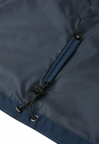 Tessuto blu navy con una texture liscia presenta un sistema a toggle e un blocco corda per una regolazione della tensione in vita.