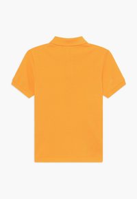 Pomarańczowa bawełniana koszulka polo z zagiętym kołnierzykiem i krótkimi rękawami. Gładka tekstura ze stębnowanymi brzegami, bez dodatkowych wzorów czy akcentów.