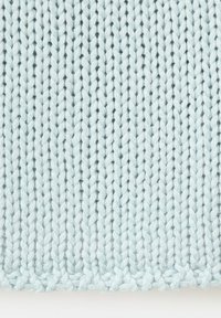 Zbliżenie na jasno-niebieską dzianinę z pionowym prążkowanym wzorem, ukazującą teksturę przędzy i szczegóły ściegów.