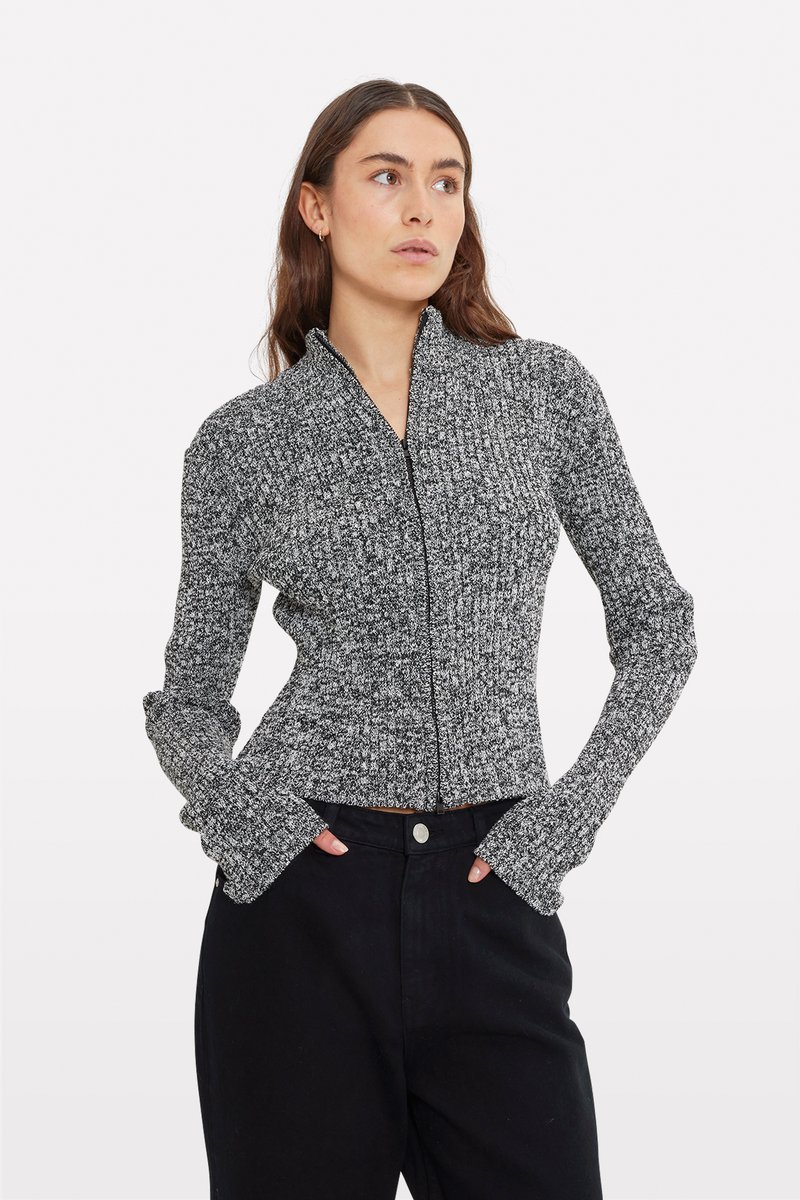 Harmaa ja musta ribattu vetoketjullinen neule, jossa on pitkät hihat ja peukalonpaikat. Neuleessa on tiivis design ja teksturoitu neulekuvio.