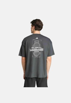 Mann trägt dunkelgraues T-Shirt mit weißem Grafikmotiv eines Kettlebells und dem Text "Global Language of Hard Work" auf der Rückseite, zeigt nach hinten.