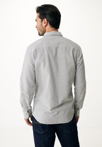 Camicia a maniche lunghe con fantasia a righe blu e bianche, colletto a punta e polsini con bottoni, realizzata in un tessuto con una texture morbida.