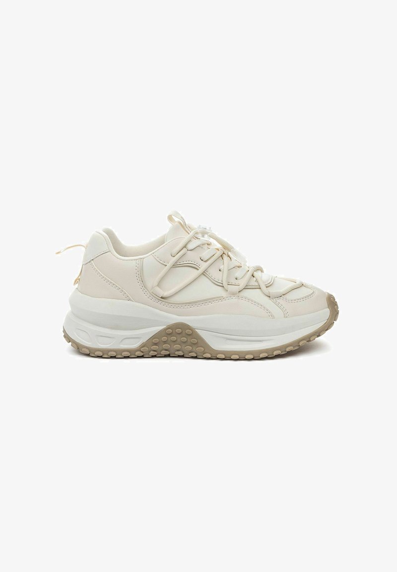 Lichtbeige sneakers met een leren bovenwerk met textuur, dikke witte tussensole en rubberen buitenzool met cirkelvormige grippatronen.