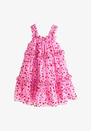 Roza haljina bez rukava s crvenim uzorcima srca, naboranim naramenicama i slojevitim naborima duž prsa i suknje.