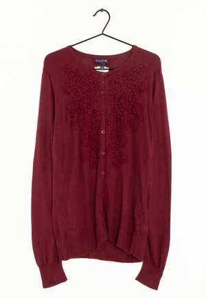 Bordowy sweter na guziki z haftem kwiatowej koronki na piersi, długimi rękawami, ściągaczami na mankietach i dole, wiszący na czarnym wieszaku.