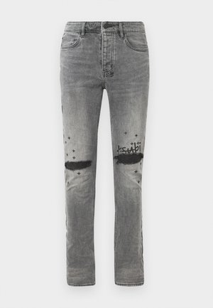 Gray denim jeans with distressed knee sections, black star accents, and a printed logo. Slim fit with standard pockets and a classic waistband.