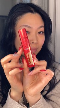 L'Oréal Paris Skin Ink i en rød plastiktube med guldtekst. Tuben er rektangulær med en hævet cirkulær logo på låget.