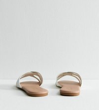 Des sandales blanches à glissière avec deux sangles ouvertes et une semelle beige, présentant une texture lisse et un design minimaliste.
