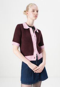 Short-sleeve sweater in burgundy and pink with a collared neckline, featuring a buttoned front and contrasting ribbed cuffs.