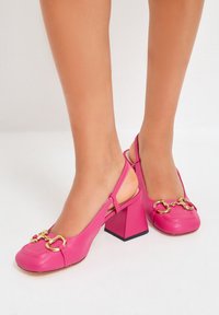 Helle rosa Slingback-Schuhe mit quadratiger Spitze, chunkigem geometrischem Absatz und goldenen Kettenakzenten. Glatte Textur, modernes Design.