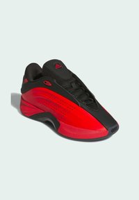 Red and black sneaker with a smooth, curved design. Features mesh material, textured accents, and a lace-up front with a rounded toe.