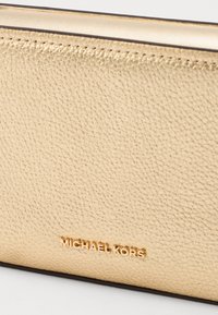 Guldfarvet læderpung med syede kanter. Har et prægget "MICHAEL KORS" logo i guld på fronten.