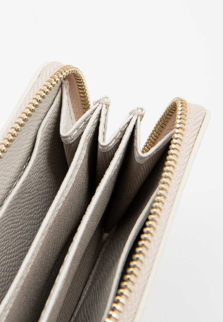 Beige Leder Geldbörse mit goldenem Reißverschluss, geöffnet und zeigt drei Hauptfächer und Stofffutter im Inneren.