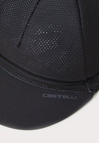Boné de ciclismo preto feito de tecido em malha respirável, apresentando uma superfície texturizada e uma pala curva com o nome da marca "Castelli" impresso em cinza.