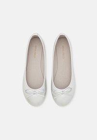 Ballerines en argent avec une finition texturée, bout arrondi et un nœud décoratif sur le dessus. L'intérieur présente un revêtement beige et une marque subtile.