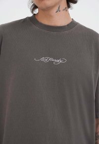 Grå bomulds t-shirt med klassisk rund hals og korte ærmer. Udsmykket med et hvidt broderet "Ed Hardy" logo på brystet.