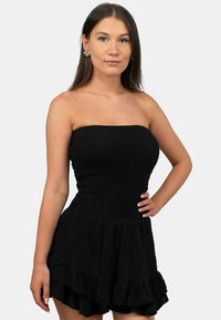 Zwarte strapless jurk met smock-bodice en gelaagde gerimpelde zoom. Gemaakt van lichtgewicht stof met een textuurafwerking.