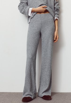Sivé široké pletené nohavice s rebrovanou textúrou, vybavené elastickým pásom a pohodlným strihom. Oblékané s voľným sivým svetrom.