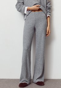 Graue, gestrickte Hosen mit weitem Bein und Rippenstruktur, ausgestattet mit einem elastischen Bund und einem lockeren Sitz. Kombiniert mit einem lockeren grauen Pullover.