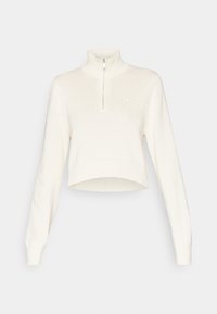 Krämfärgad kortärmad tröja med långa ärmar och en kvartdragkedja i hög krage, ribbade manchetter och fåll.