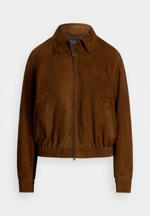 Pruun süsijakk, millel on krae, elastne äär ja tõmblukuga sulgemine. Omab külgtaskuid ja peent logo rinnal.