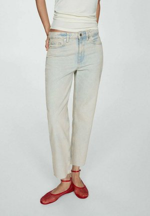 Hellblau gewaschene Jeans mit lockerer Passform, geraden Beinen und ausgefransten Säumen, kombiniert mit roten Mesh-Ballerinas mit Knöchelriemchen.