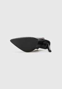Scarpa nera con punta appuntita, superiore testurizzato, tacco sottile e suola liscia. Presenta un piccolo accento dorato sul lato.