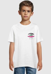 Hvid bomulds T-shirt med et lille farverigt UFO-grafik og teksten "OUT OF THIS WORLD" ovenfor, korte ærmer og en rund halsudskæring.