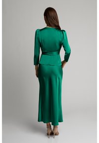 Sukienka z satyny w kolorze szmaragdowej zieleni z dopasowaną górą, peplum w talii i długimi rękawami, spływająca do pełnej długości spódnicy. Gładka tekstura, minimalistyczny design.