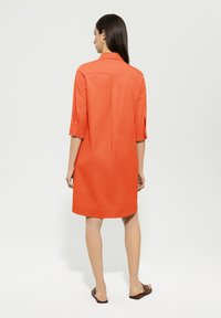 Orange, knielanges Kleid mit einem Kragen und dreiviertel Ärmeln. Verfügt über einen geraden Schnitt und eine Rückennaht.