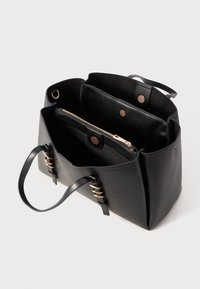 Schwarze Ledertrage Tasche mit goldenen Beschlägen, mit offenem Oberteil, innerem Reißverschlussfach und zwei Griffen. Glatte Textur, strukturierte Form.