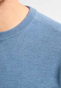 Lichtblauwe gebreide trui met een ribgebreide ronde hals. De stof heeft een gladde textuur met een subtiele, gelijkmatige weving.