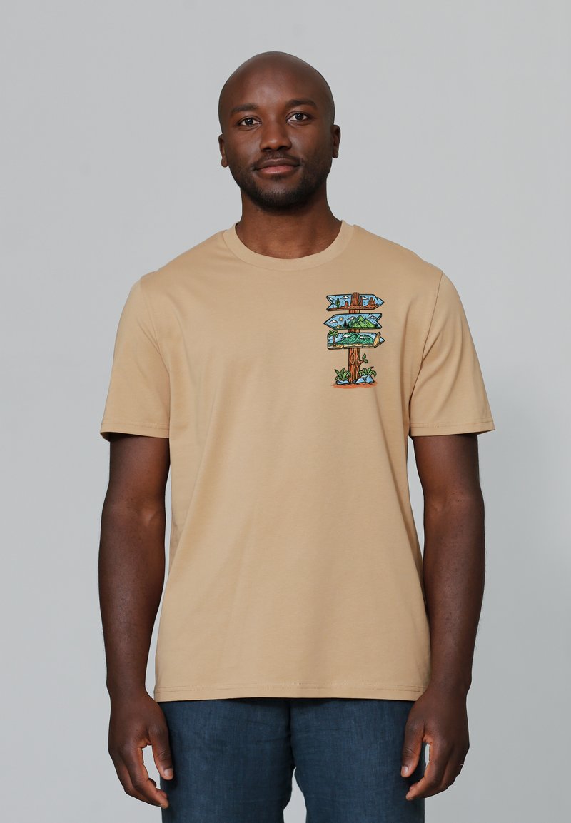 Beige T-shirt met korte mouwen en een kleurrijke grafische print van richtingaanwijzers op de linkerkant van de borst. Gemaakt van zacht katoen.