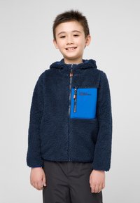 Veste en polaire zippée de couleur bleu marine avec des accents bleus, surface texturée, capuche et poche poitrine zippée.