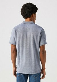 Męska koszulka polo z krótkim rękawem w heatherowym niebieskim kolorze. Posiada kołnierzyk, prosty dół i strukturalny wzór z tyłu.