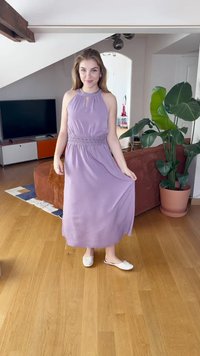 Vestido maxi lavanda com decote halter e um buraco chave, detalhes na cintura franzida e tecido fluido. Combinado com sapatos brancos slip-on.