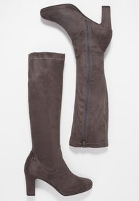 Botas gris de ante por encima de la rodilla con un tacón cuadrado, que cuentan con un cierre lateral, una textura suave y un ajuste contorneado para la pierna.