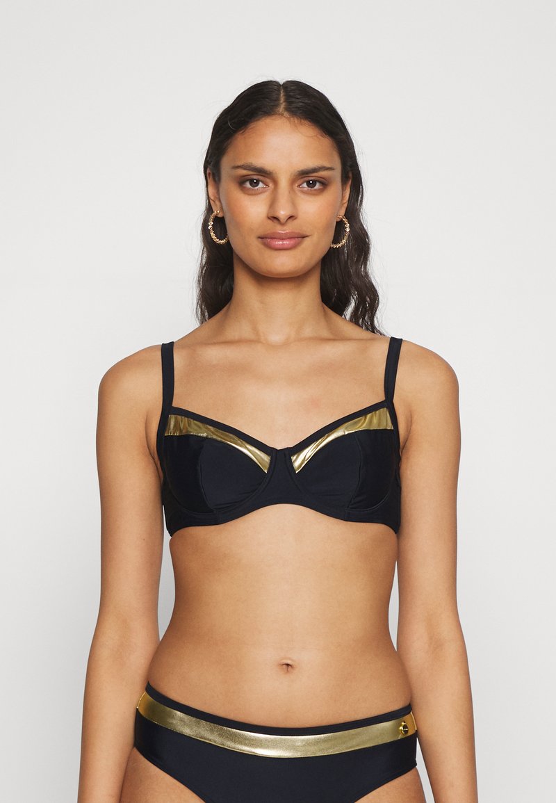 Juodas bikini viršus su auksinėmis detalėmis, pasižymintis struktūrizuotu kirpimu, reguliuojamomis petnešėlėmis ir lygiu paviršiumi. Suderinamos kelnaitės su auksine juostele.