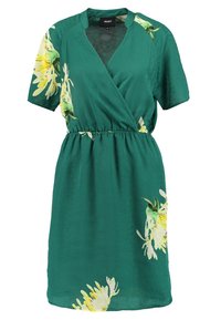Robe verte à manches courtes, avec taille élastique, ornée d'un imprimé floral jaune. Tissu lisse, design jusqu'au genou avec un décolleté en V.