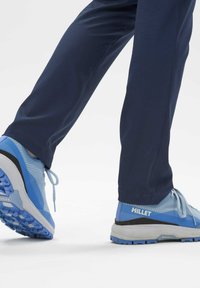 Chaussures de randonnée bleu clair avec une tige en mesh texturé, accents noirs et semelle robuste, associées à un pantalon bleu marine à la finition lisse.