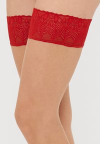 Piros csipke combfix virágmintával és texturált szegéllyel a tetején, amely úgy van tervezve, hogy gartnerekkel biztosan a helyén maradjon.