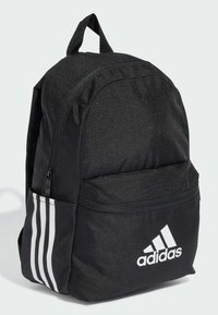 Mochila negra hecha de tela texturizada, con un bolsillo frontal, cremalleras grises y tres rayas blancas en un lado con el logo de Adidas.