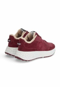 Baskets en suede bordeaux avec une semelle texturée blanche et un intérieur beige doux. Présente un logo sur le côté et des motifs distincts à l'avant et sur la semelle.